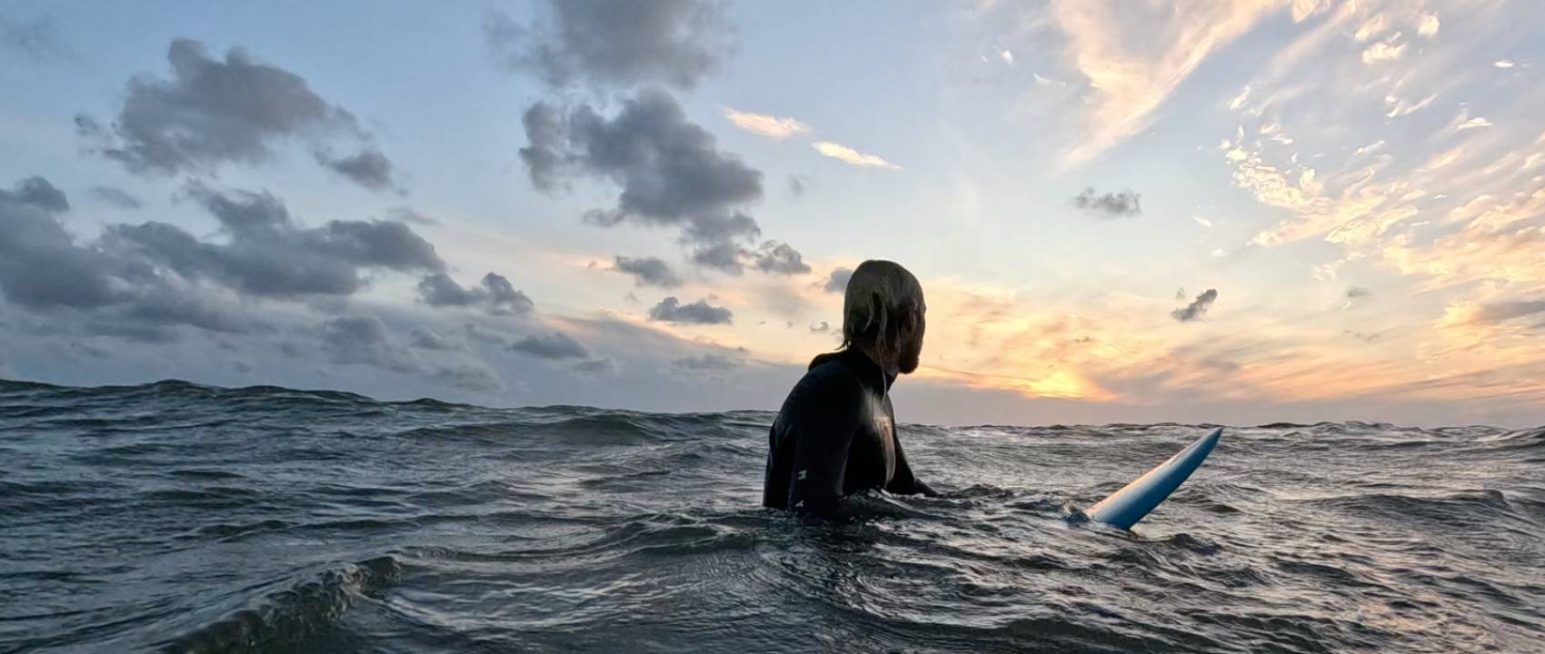 Surfer blickt auf den Sonnenuntergang auf dem Meer