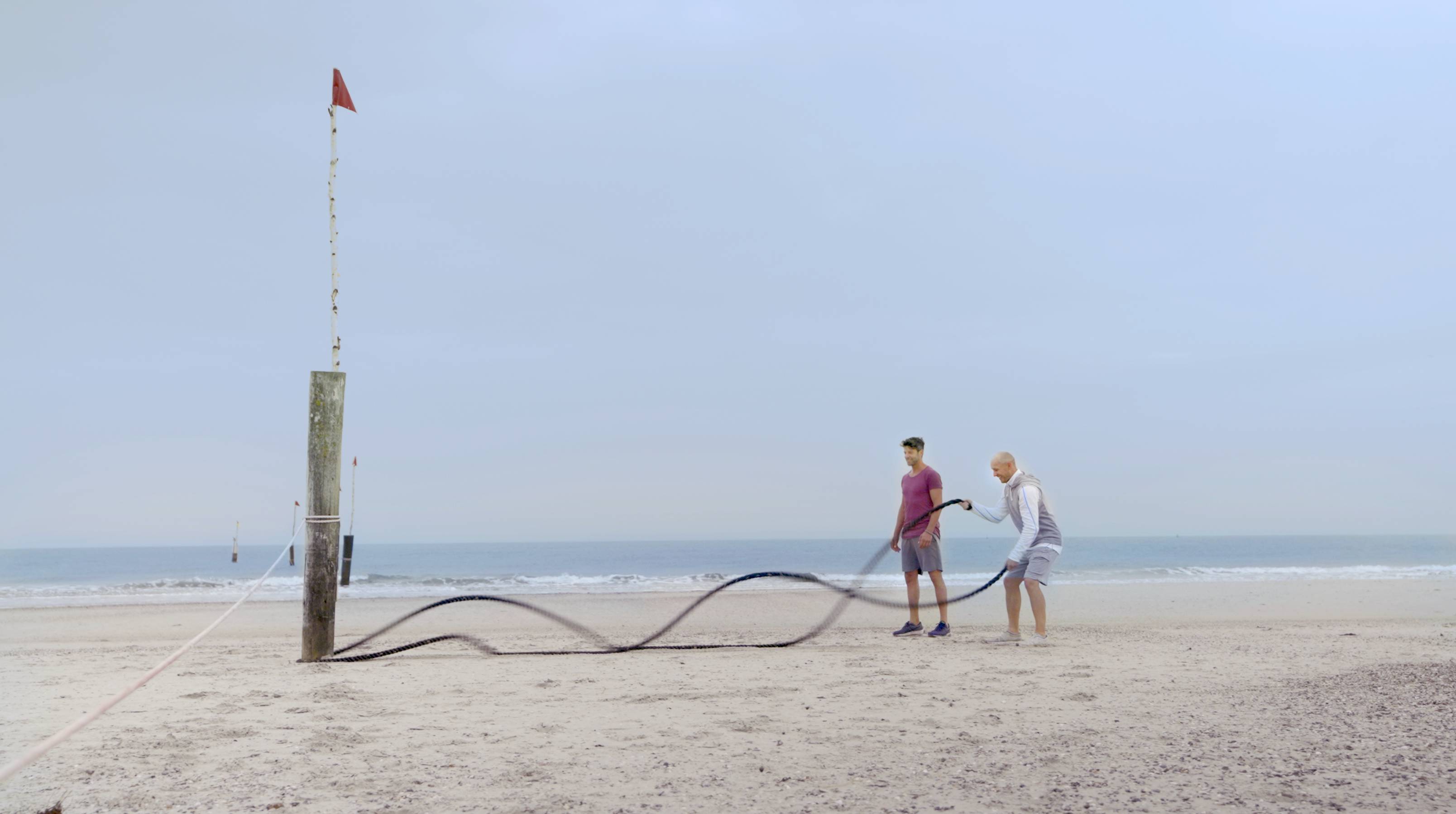 Männer trainieren mit Seilen am Strand