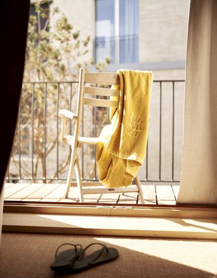 Balkon mit Holzstuhl in der Sonne