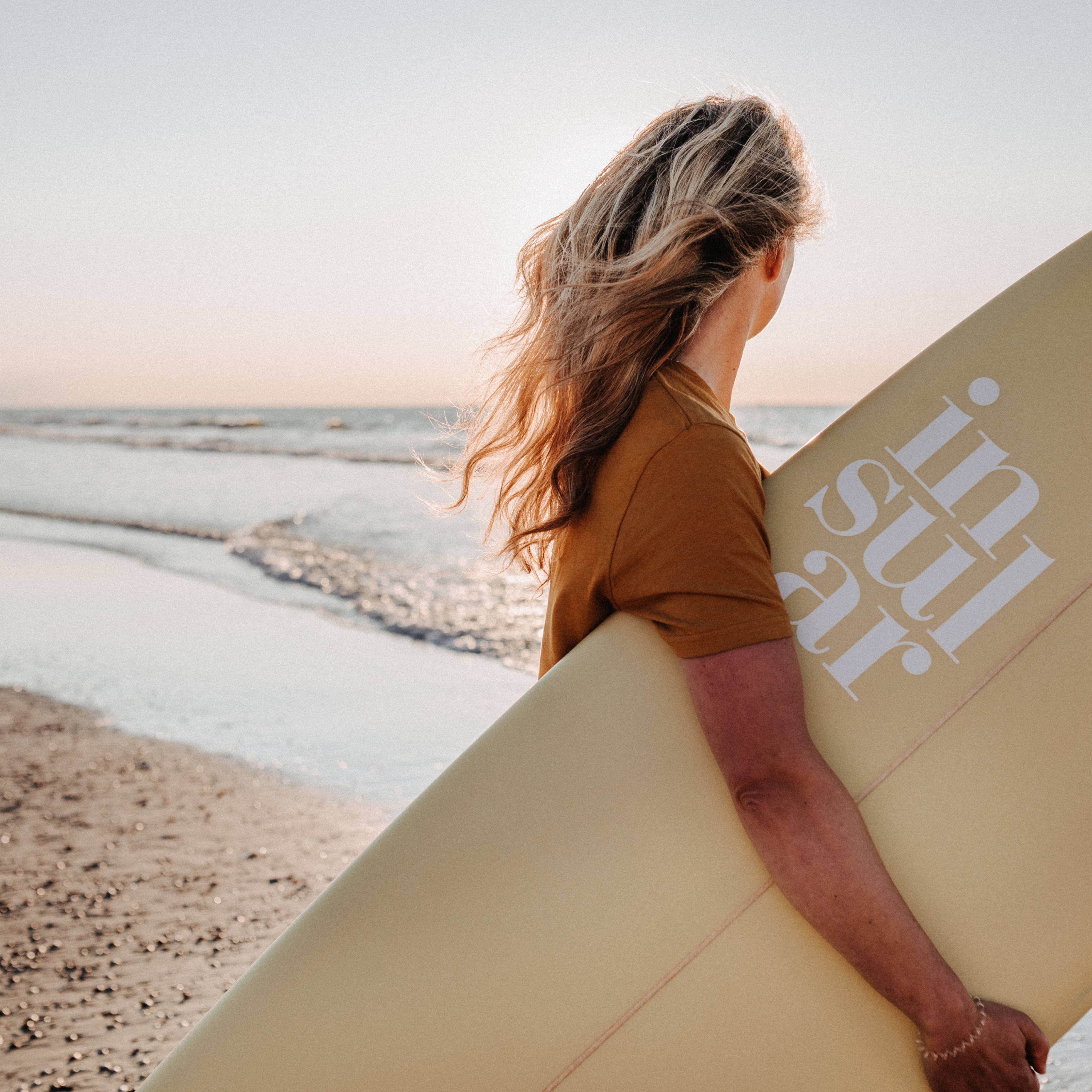 Frau trägt Surfbrett an den Strand von Norderney